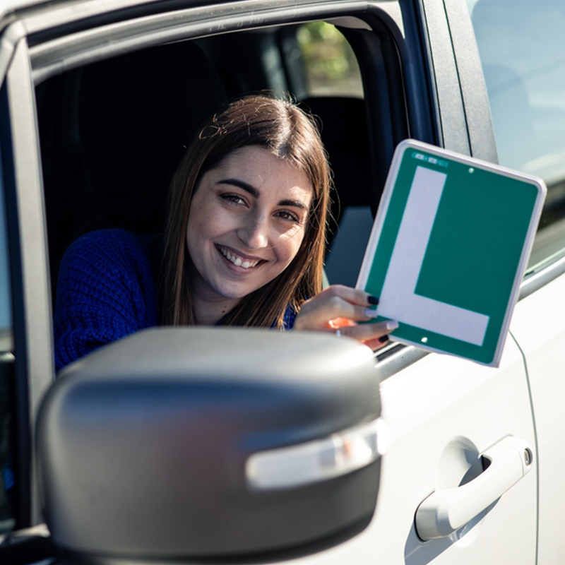 chica en un coche con la placa de principiante