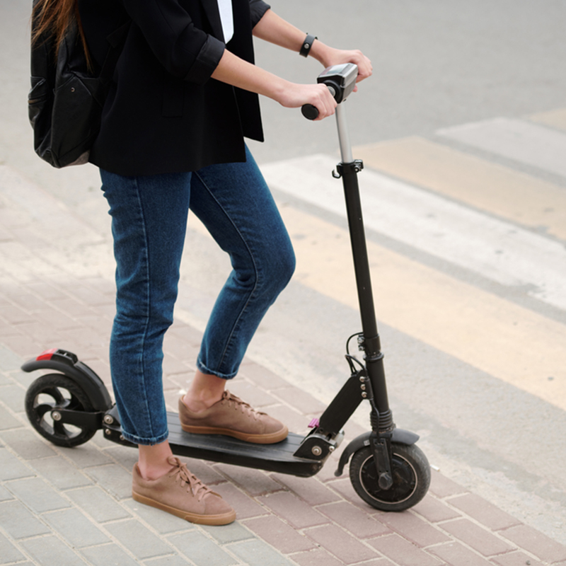 girl's legs carrying an electric scooter